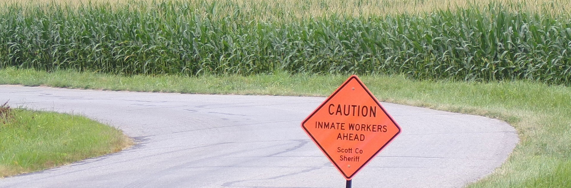 Caution sign next to the road reading, 'Inmate Workers Ahead - Scott Co Sheriff'